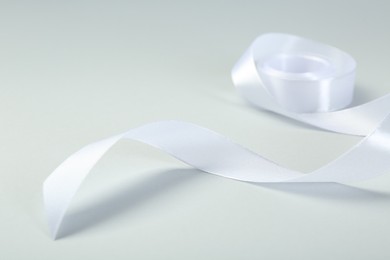 Photo of Beautiful white ribbon reel on light background, closeup