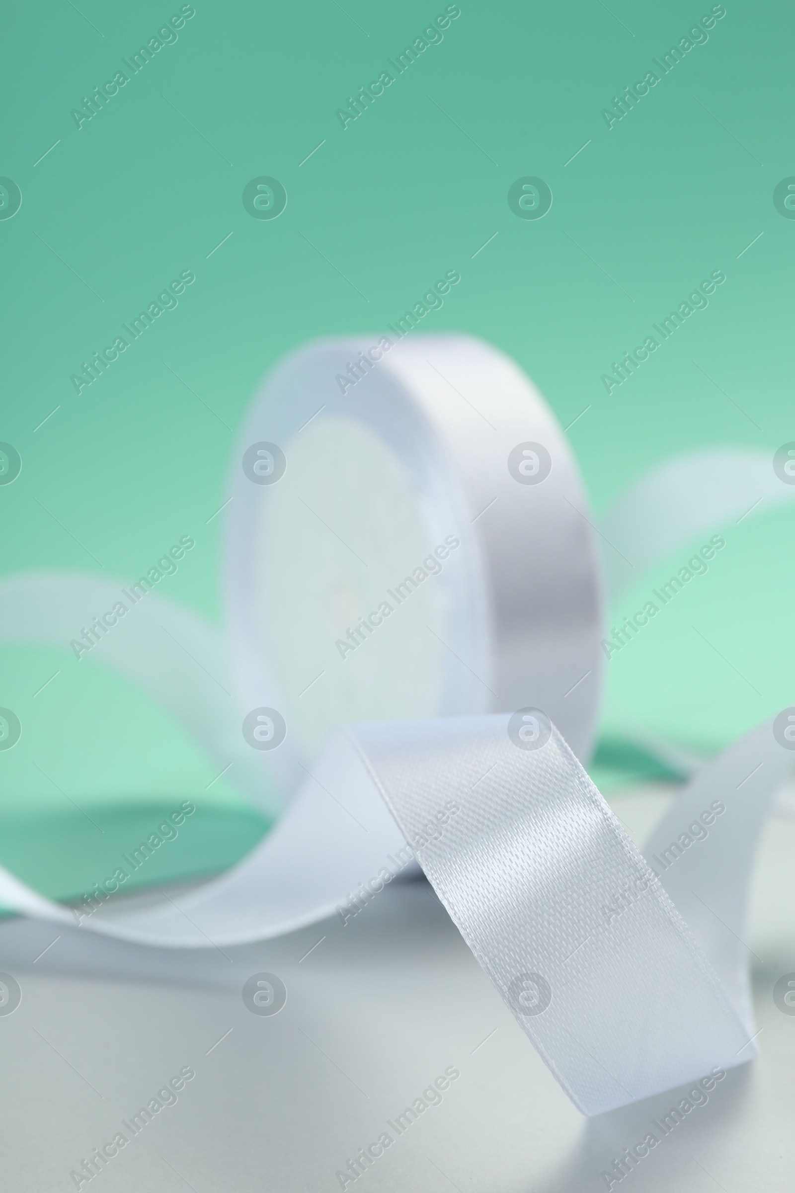 Photo of Beautiful white ribbon reel on color background, closeup