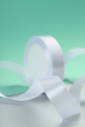 Beautiful white ribbon reel on color background, closeup