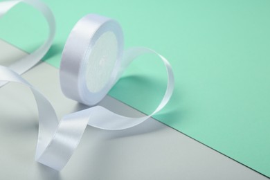 Beautiful white ribbon reel on color background, closeup. Space for text
