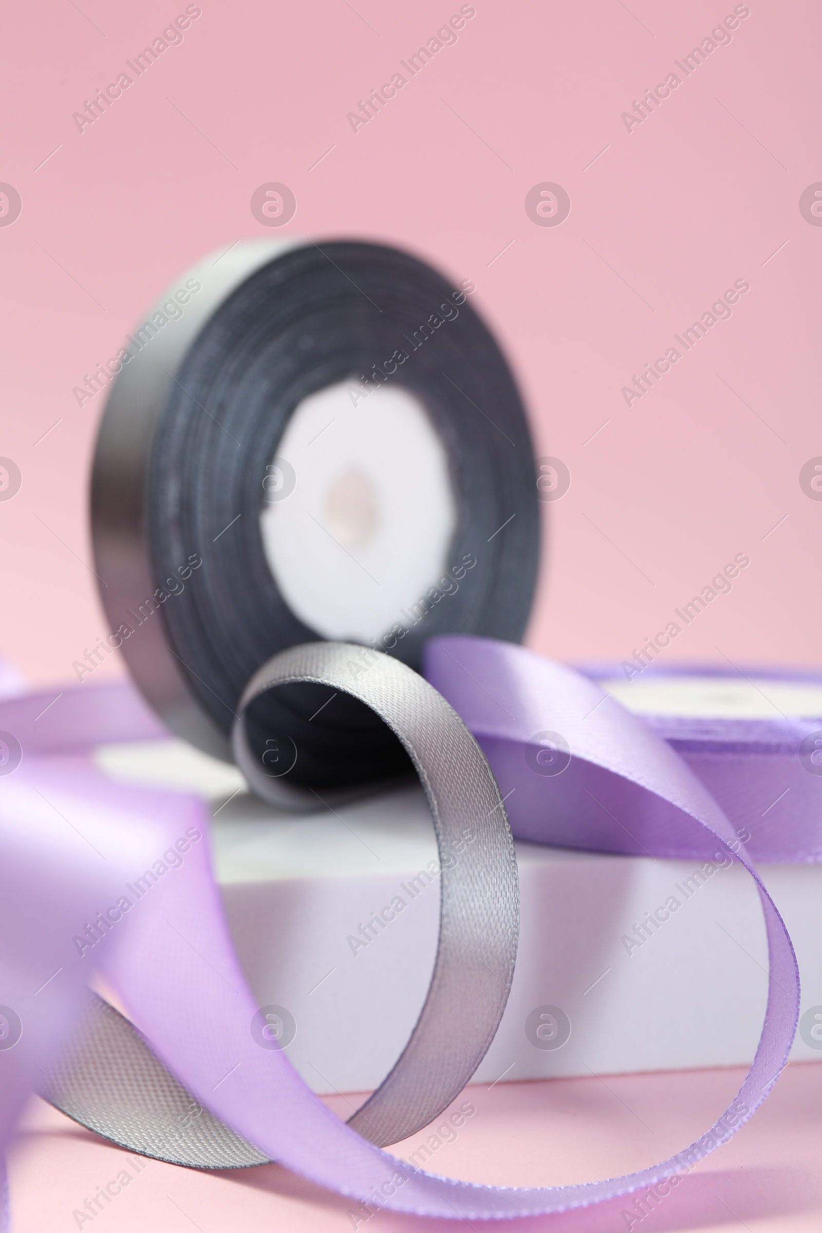 Photo of Ribbon reels in different colors on pink background, closeup view