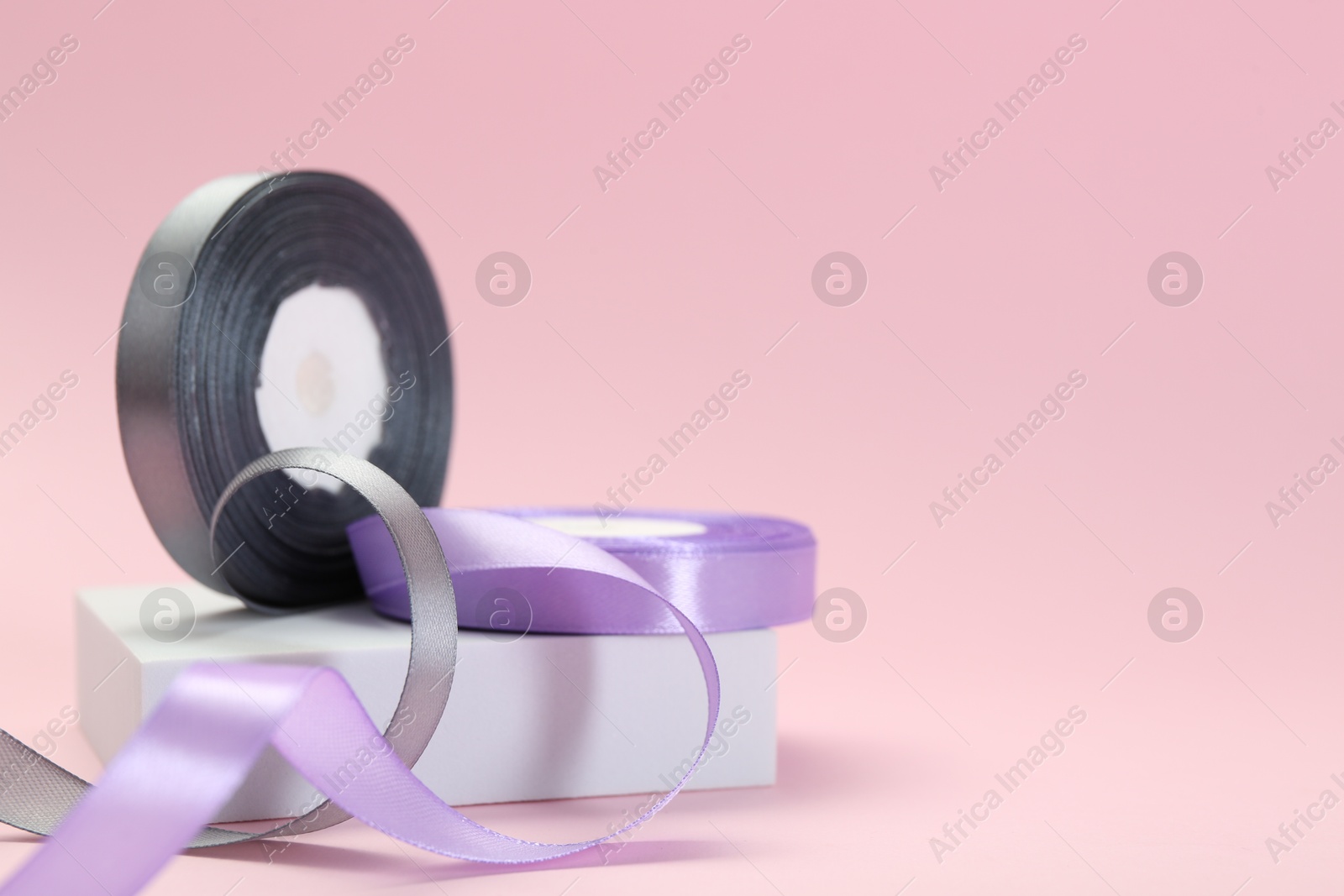 Photo of Ribbon reels in different colors on pink background, closeup. Space for text