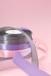 Ribbon reels in different colors on pink background, closeup view