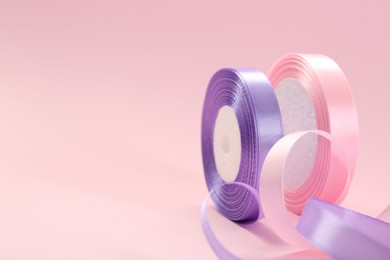 Photo of Ribbon reels in different colors on pink background, closeup. Space for text