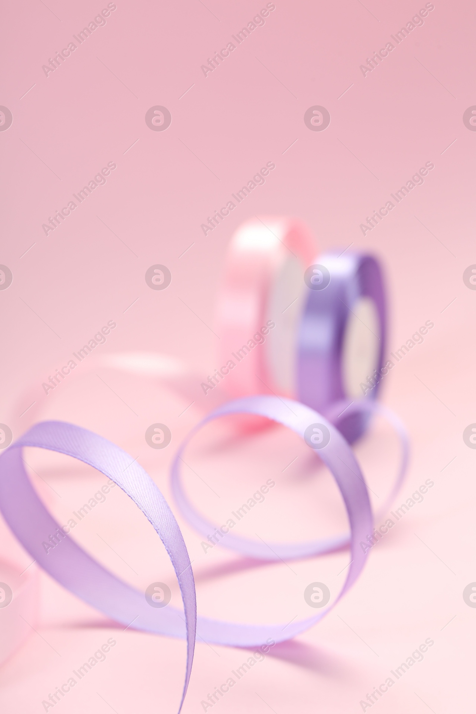 Photo of Ribbon reels in different colors on pink background, closeup view