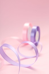 Ribbon reels in different colors on pink background, closeup view