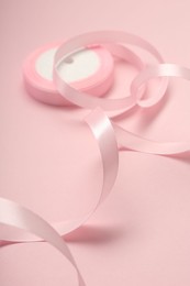 Photo of Beautiful ribbon reel on pink background, closeup