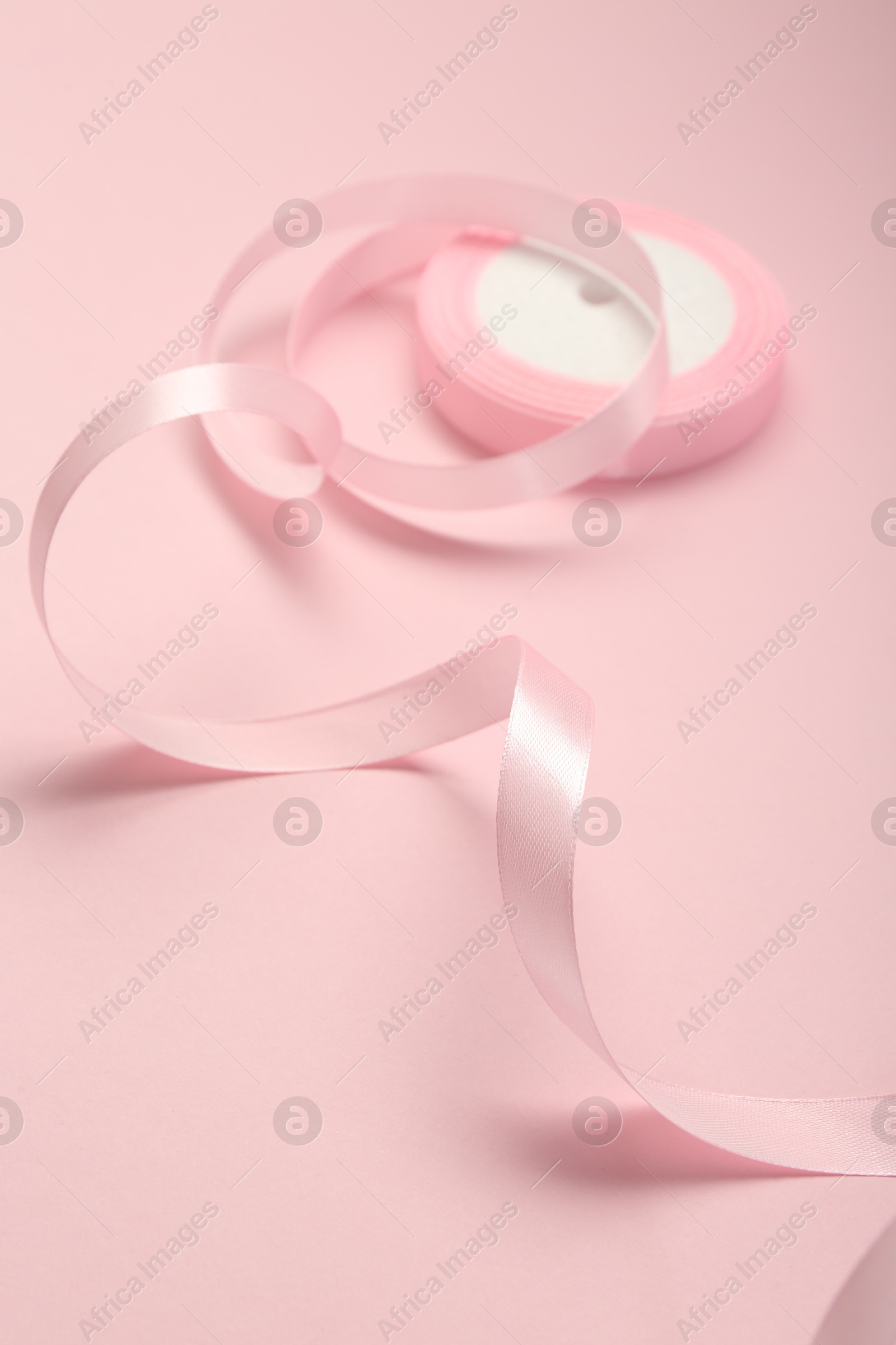 Photo of Beautiful ribbon reel on pink background, closeup