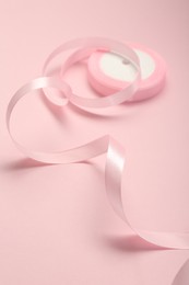 Photo of Beautiful ribbon reel on pink background, closeup