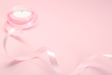Photo of Beautiful ribbon reel on pink background, closeup. Space for text