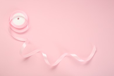 Photo of Beautiful ribbon reel on pink background, top view. Space for text