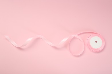 Photo of Beautiful ribbon reel on pink background, top view