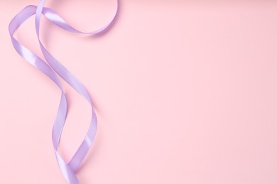 Beautiful violet ribbon on pink background, top view. Space for text