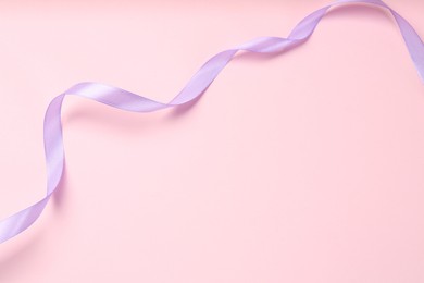 Photo of Beautiful violet ribbon on pink background, top view. Space for text
