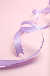 Beautiful violet ribbon on pink background, closeup