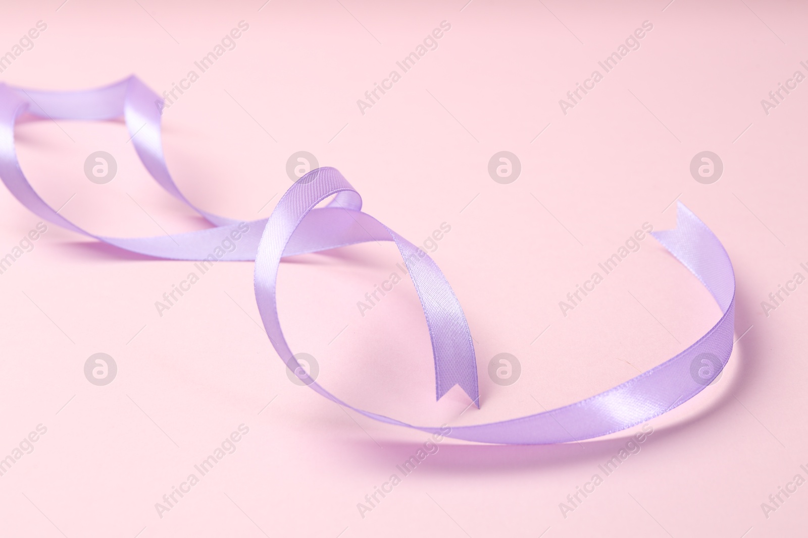 Photo of Beautiful violet ribbon on pink background, closeup