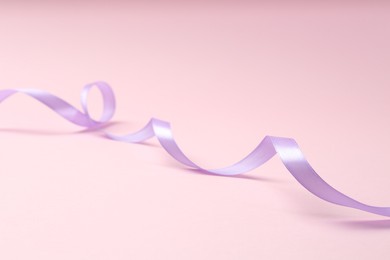 Photo of One beautiful violet ribbon on pink background