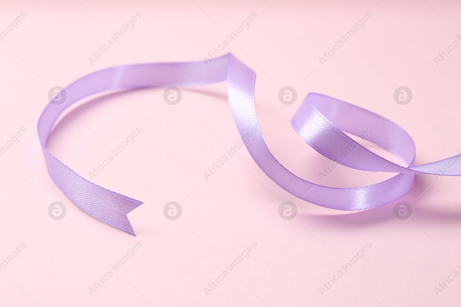 Photo of Beautiful violet ribbon on pink background, closeup