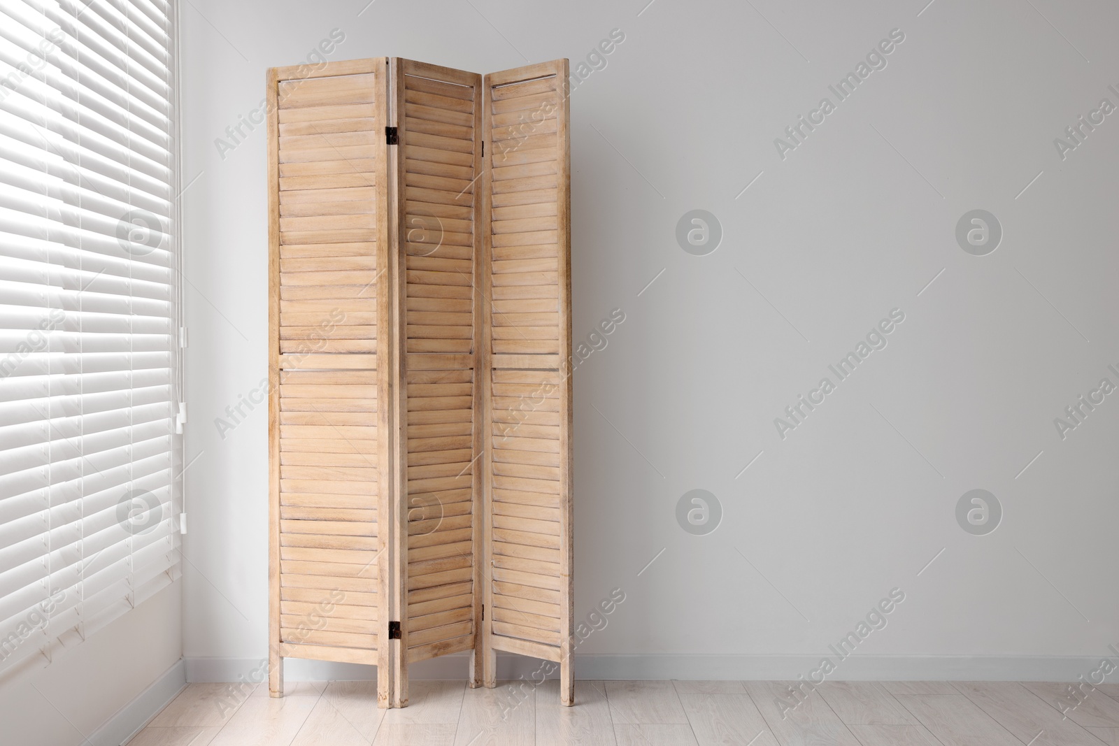 Photo of Wooden folding screen near white wall indoors, space for text