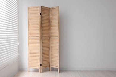 Photo of Wooden folding screen near white wall indoors, space for text