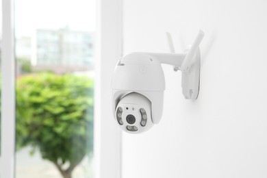Modern CCTV camera on white wall indoors