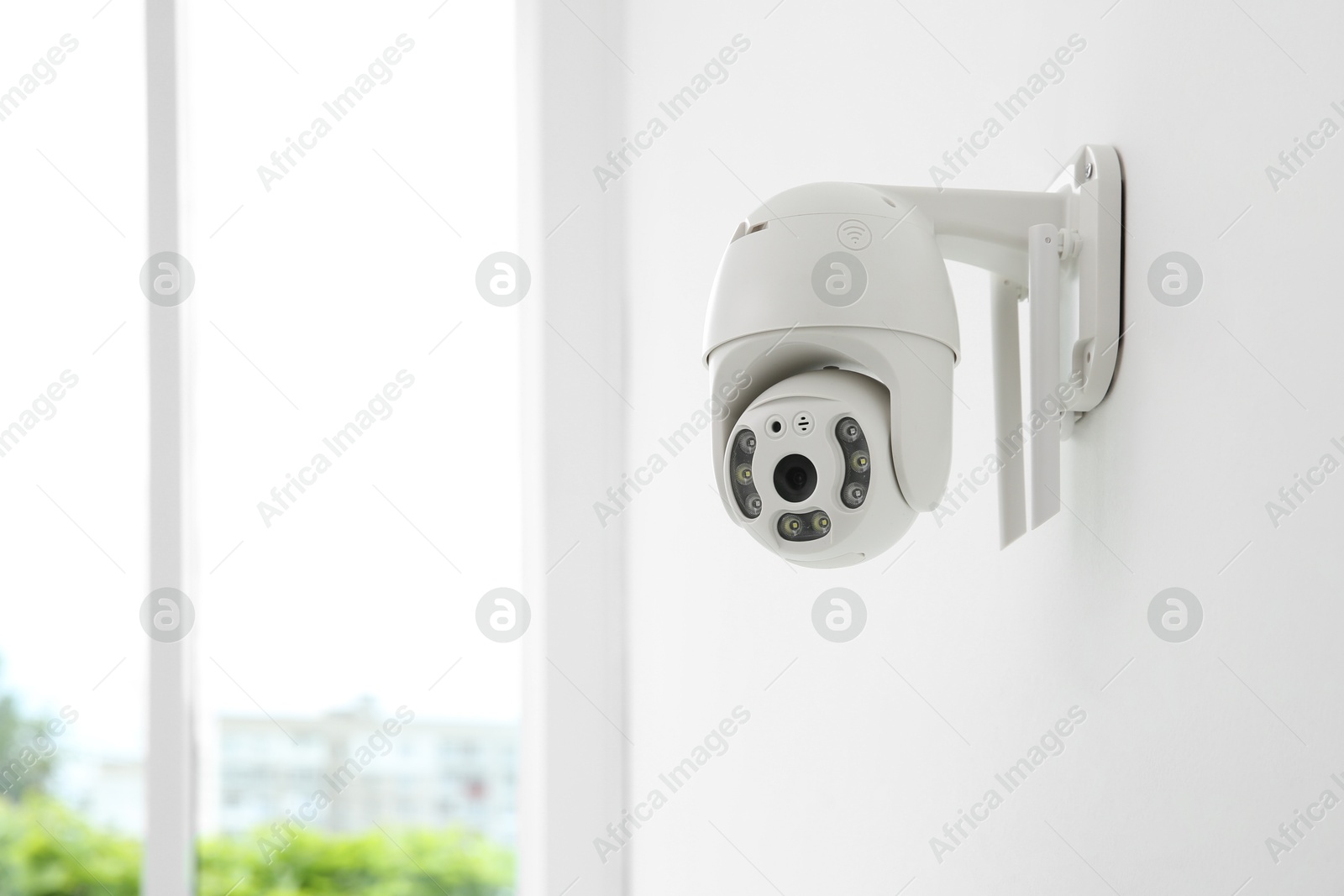 Photo of CCTV camera on white wall indoors, space for text