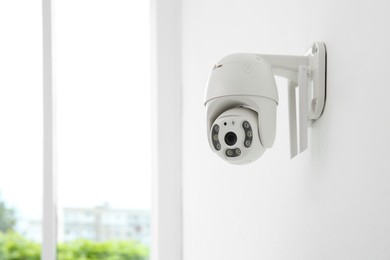 CCTV camera on white wall indoors, space for text
