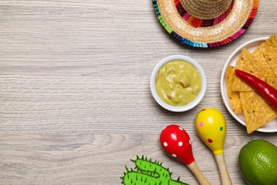 Flat lay composition with guacamole and Mexican sombrero hat on wooden table, space for text