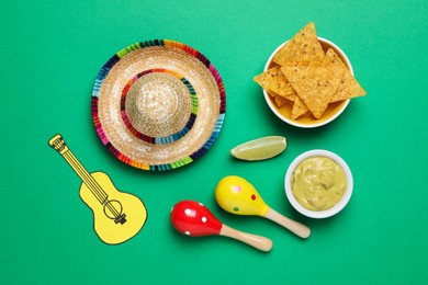 Photo of Mexican sombrero hat, nachos chips, guacamole, maracas, lime and paper guitar on green background, flat lay
