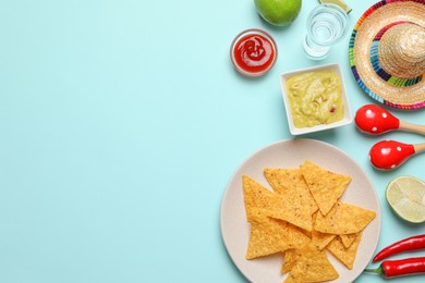 Photo of Flat lay composition with nachos chips and Mexican sombrero hat on light blue background, space for text