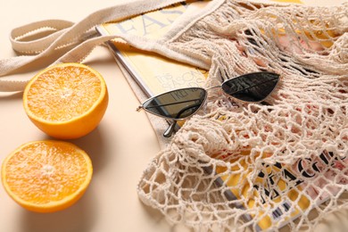 String bag, magazine, sunglasses and halves of orange on beige background