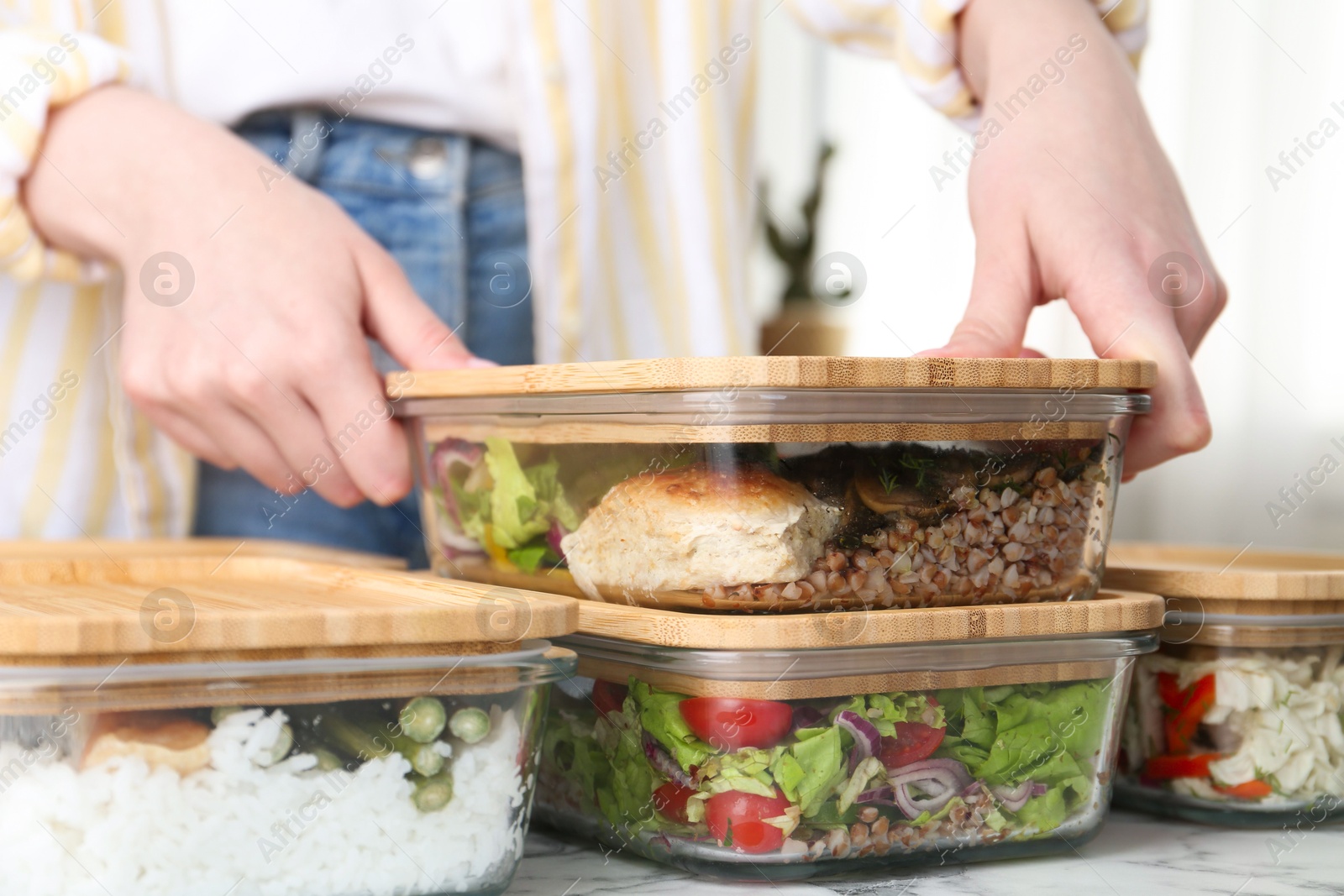 Photo of Healthy food. Woman closing glass container with meal at white marble table, closeup