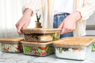 Healthy food. Woman closing glass container with meal at white marble table, closeup