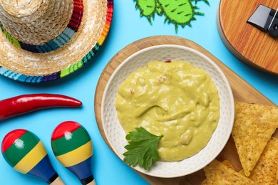 Photo of Flat lay composition with Mexican sombrero hat and guacamole on light blue background