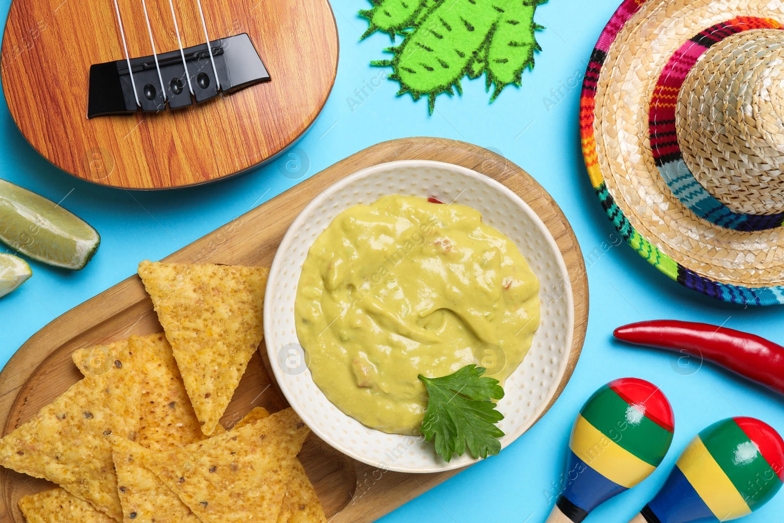 Photo of Flat lay composition with Mexican sombrero hat and guacamole on light blue background