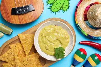 Flat lay composition with Mexican sombrero hat and guacamole on light blue background