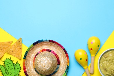 Mexican sombrero hat, nachos chips, guacamole, maracas and paper cactus on color background, flat lay. Space for text