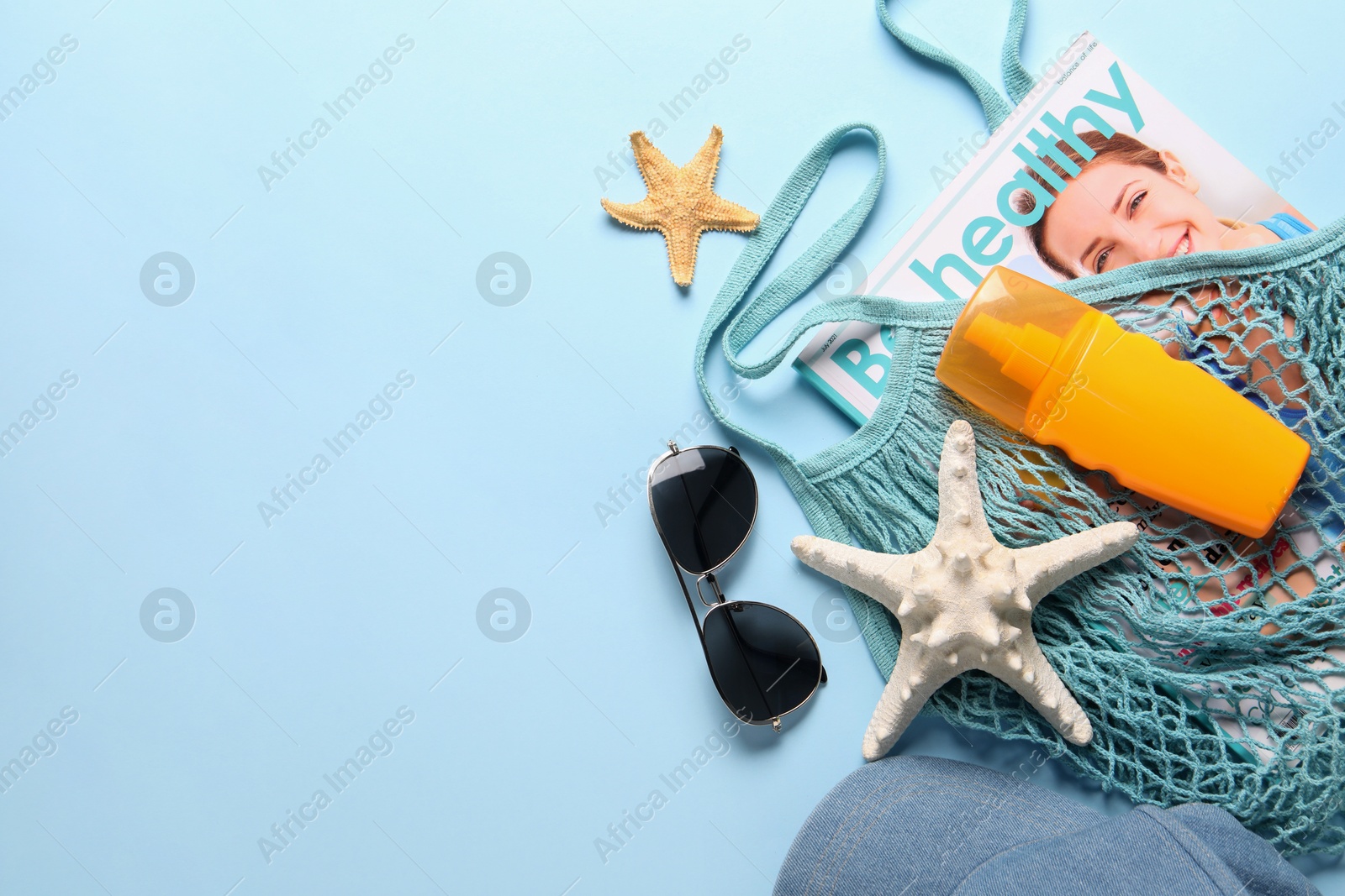 Photo of String bag and different beach accessories on light blue background, top view