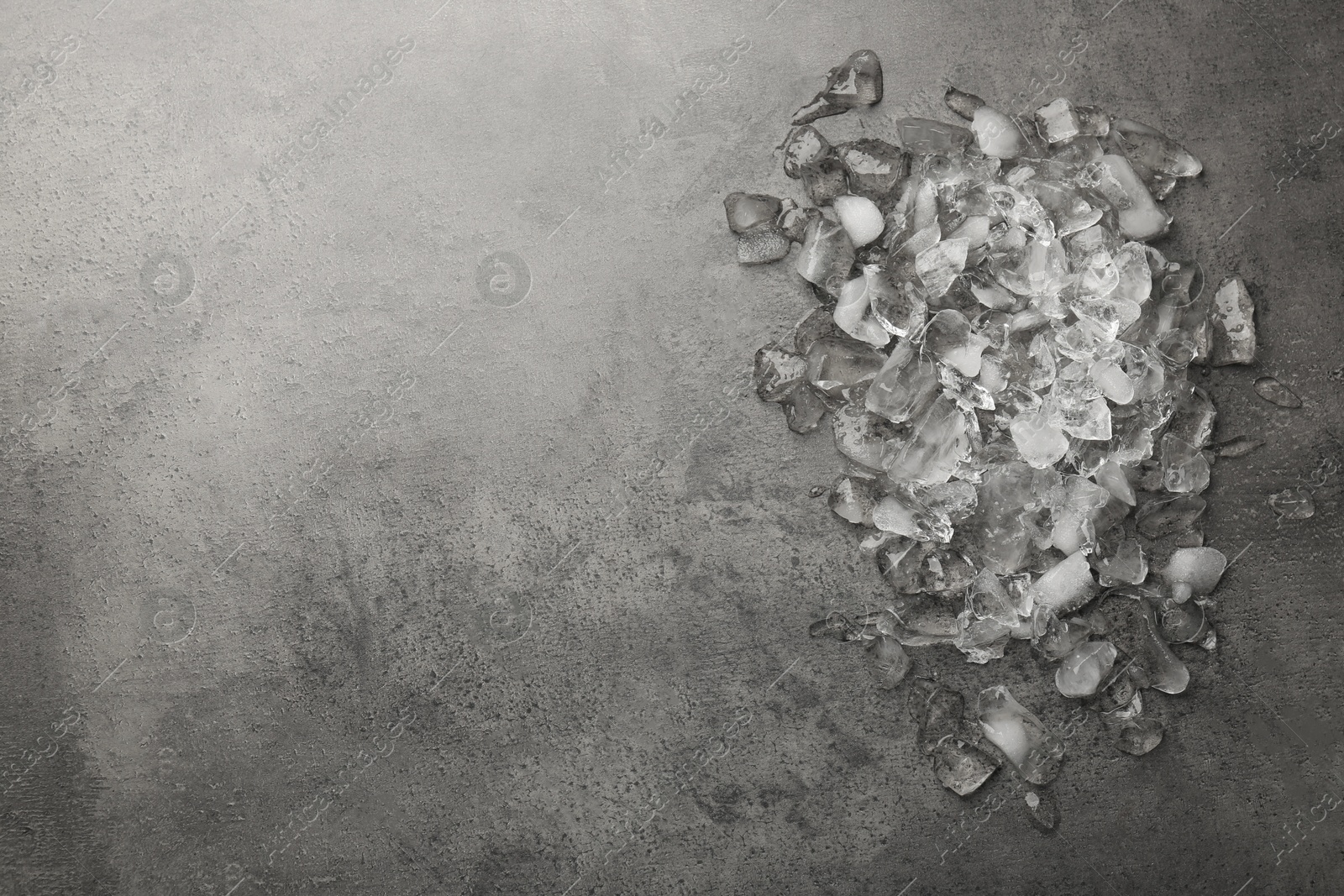 Photo of Pile of crushed ice on dark textured table, top view. Space for text