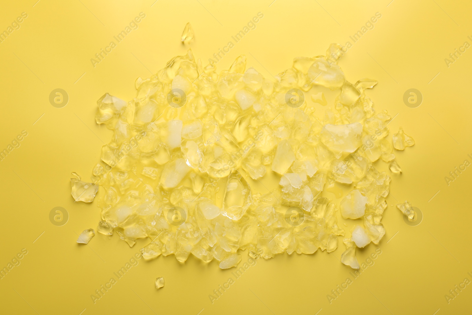 Photo of Pile of crushed ice on yellow background, top view