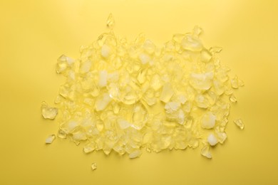Photo of Pile of crushed ice on yellow background, top view