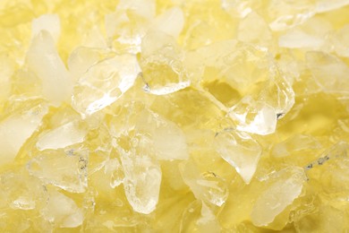 Photo of Many pieces of crushed ice on yellow background, closeup