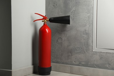 Photo of Fire extinguisher on floor near grey wall indoors