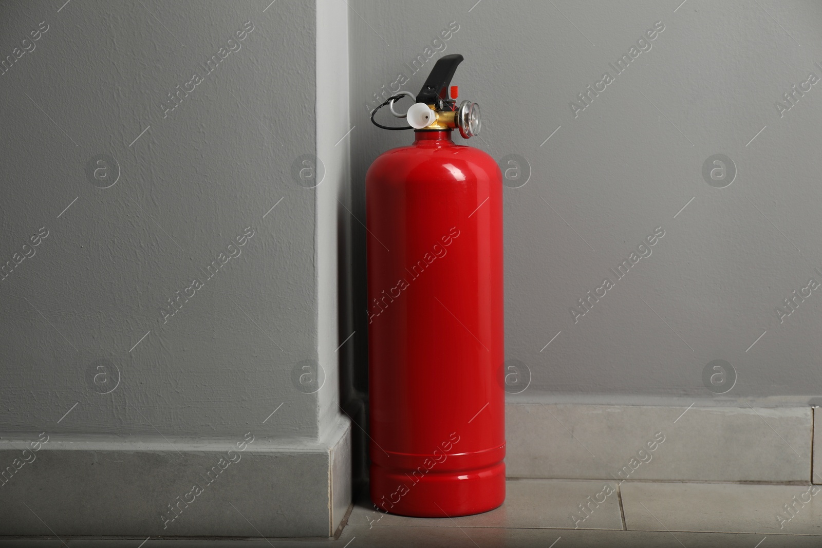 Photo of Fire extinguisher on floor near grey wall indoors