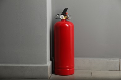 Photo of Fire extinguisher on floor near grey wall indoors