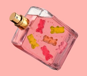 Image of Perfume bottle with sweet gummy bears inside on coral color background, creative collage