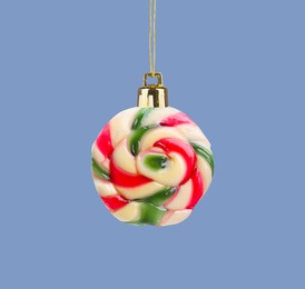 Sweet candy with string like Christmas ball on pale blue background, creative collage