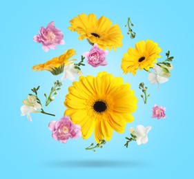 Yellow gerberas and other beautiful flowers in air on light blue background