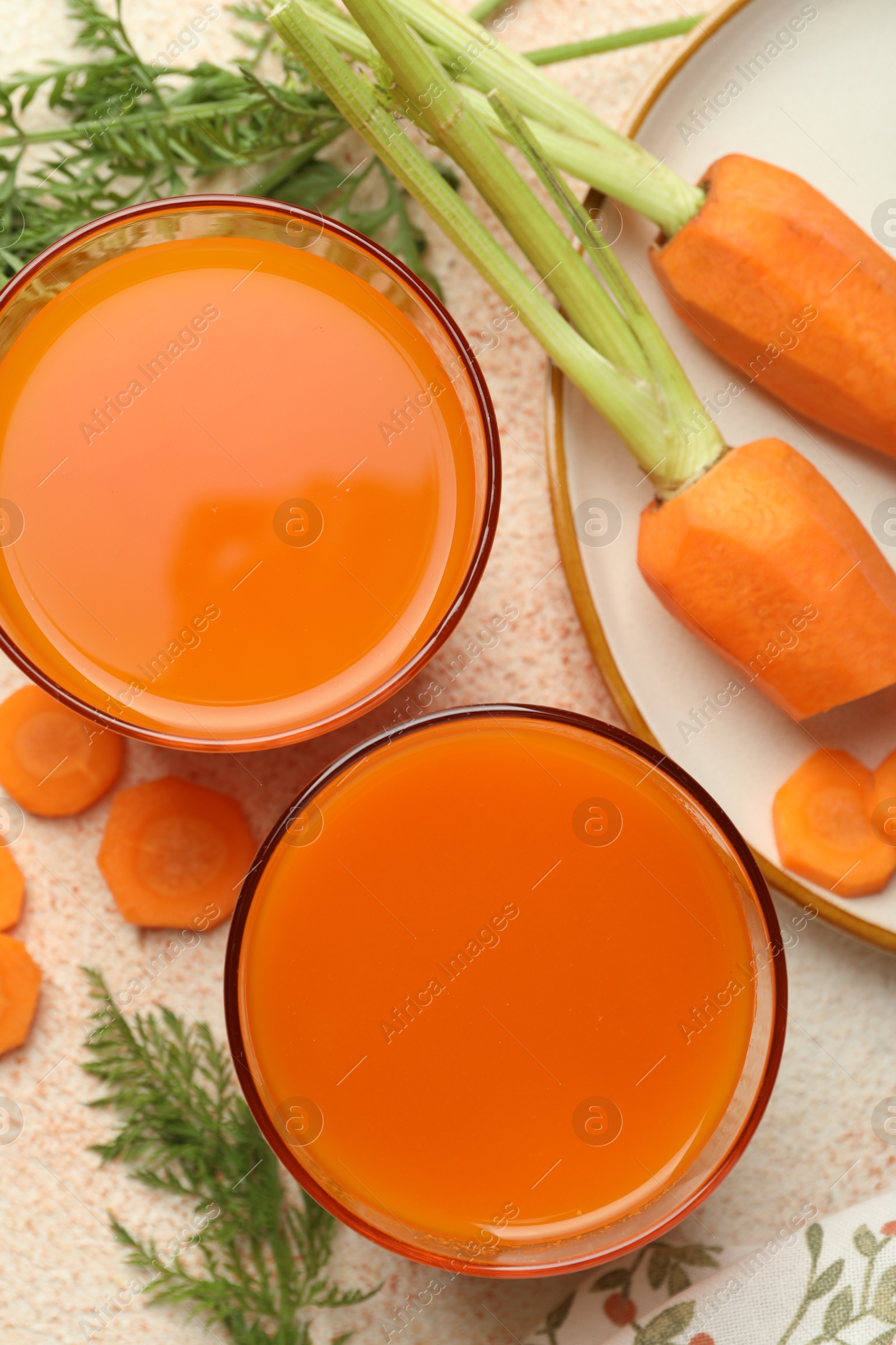 Photo of Healthy carrot juice in glasses and fresh vegetables on color textured table, top view