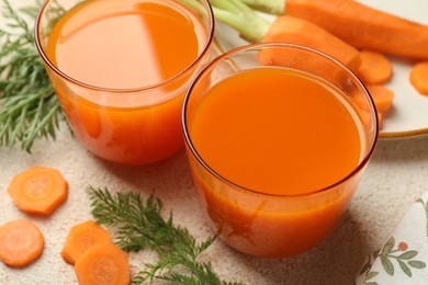 Photo of Healthy carrot juice in glasses and fresh vegetables on color textured table, closeup